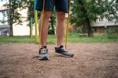 Orta yaşlı bir adam parkta direniş bantlarıyla güç egzersizleri yapıyor. Yüksek kalite fotoğraf