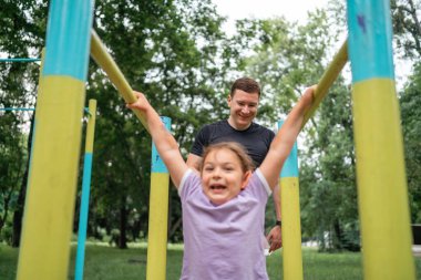 Babası ve çocuğu açık alanda barfiks çekiyorlar. Sağlıklı aktif yaşam tarzı, mutlu aile zamanı. Modern babalık kavramı. Yüksek kalite fotoğraf