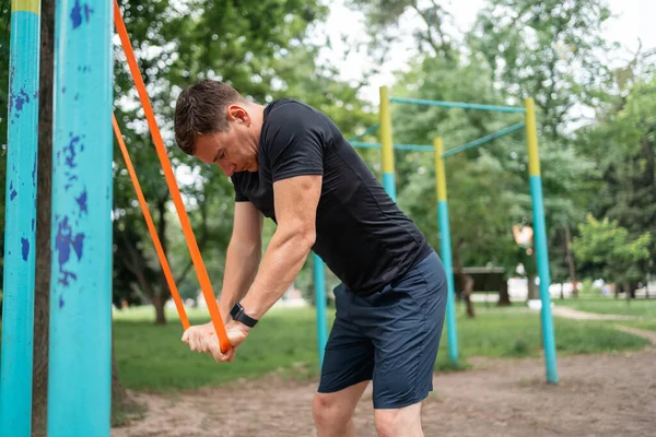 stock image Middle age man doing strength exercises with resistance bands outdoors in park . High quality photo