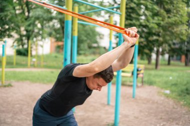 Orta yaşlı bir adam parkta direniş bantlarıyla güç egzersizleri yapıyor. Yüksek kalite fotoğraf
