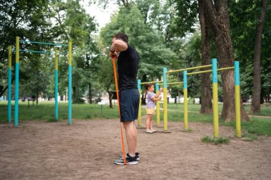 Orta yaşlı bir adam parkta direniş bantlarıyla güç egzersizleri yapıyor. Yüksek kalite fotoğraf