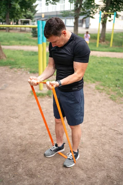 stock image Middle age man doing strength exercises with resistance bands outdoors in park . High quality photo