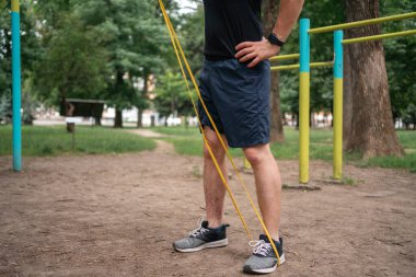 Orta yaşlı bir adam parkta direniş bantlarıyla güç egzersizleri yapıyor. Yüksek kalite fotoğraf