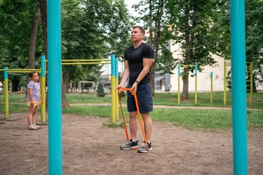 Orta yaşlı bir adam parkta direniş bantlarıyla güç egzersizleri yapıyor. Yüksek kalite fotoğraf