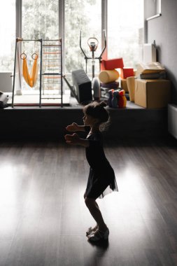 Eğitim sırasında dans stüdyosunda siyah spor mayo giyen kız çocuğu. 45 yaşında anaokulu öğrencisi. Sağlıklı fiziksel gelişim. Yüksek kalite fotoğraf