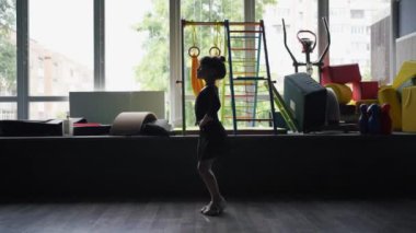 Eğitim sırasında dans stüdyosunda siyah spor mayo giyen kız çocuğu. 45 yaşında anaokulu öğrencisi. Sağlıklı fiziksel gelişim. Yüksek kalite fotoğraf