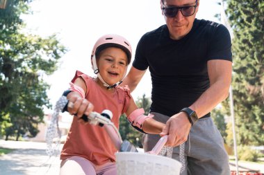 Babası parkta bisiklet sürmeyi öğretiyor. İşinin ehli bir babanın çocuğuyla kaliteli limon alması. - Evet. Yüksek kalite fotoğraf