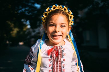 Geleneksel Ukrayna kıyafetleri ve çiçek çelengi giyen kız çocuğu gün ışığında dışarıda dua ediyor. Geleneksel Ukrayna kültürü, Slav çocuk. Yüksek kalite fotoğraf