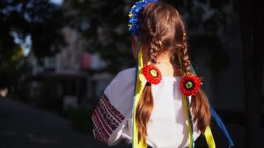 Geleneksel Ukrayna kıyafetleri ve çiçek çelengi giyen kız çocuğu gün ışığında dışarıda dua ediyor. Geleneksel Ukrayna kültürü, Slav çocuk. Yüksek kalite 4k görüntü