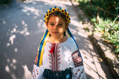 Geleneksel Ukrayna kıyafetleri ve çiçek çelengi giyen kız çocuğu gün ışığında dışarıda dua ediyor. Geleneksel Ukrayna kültürü, Slav çocuk. Yüksek kalite fotoğraf