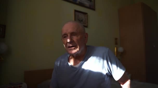 自宅の高齢者が日光浴で寝室のベッドに座っている 孤独な定年退職という概念 高品質の4K映像 — ストック動画