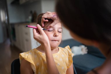 Pembe göz kalemiyle çocuk makyajı yapan bir makyöz. Küçük kız partisi ya da doğum günü hazırlığı. - Evet. Yüksek kalite fotoğraf