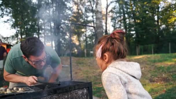 中年白人父亲男人 带着小女孩 一边向煤气炉里吹气 一边烤着火锅 户外烧烤派对 简单美味的食物着火了 高质量的4K镜头 — 图库视频影像