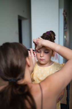 Pembe göz kalemiyle çocuk makyajı yapan bir makyöz. Küçük kız partisi ya da doğum günü hazırlığı. - Evet. Yüksek kalite fotoğraf