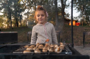 Parkta ya da arka bahçede ızgara mantarlı çocuk. 5-6 yaşlarında bir çocuk hafta sonunu ailesiyle dışarıda geçirecek. Yüksek kalite fotoğraf
