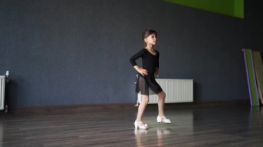 Eğitim sırasında dans stüdyosunda siyah spor mayo giyen kız çocuğu. 45 yaşında anaokulu öğrencisi. Sağlıklı fiziksel gelişim. Yüksek kalite fotoğraf