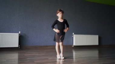 Eğitim sırasında dans stüdyosunda siyah spor mayo giyen kız çocuğu. 45 yaşında anaokulu öğrencisi. Sağlıklı fiziksel gelişim. Yüksek kalite fotoğraf
