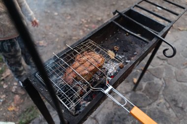 Kafkasyalı yakın çekim eller dışarıda kömür filesinin ızgarasında biftek pişiriyor. Arka bahçe bbq partisi yaz ya da sonbaharda. Yüksek kalite 4k görüntü