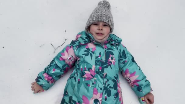 穿着冬装的小女孩躺在白雪上 成了雪天使 孩子们在户外的快乐心情 高质量的4K镜头 — 图库视频影像