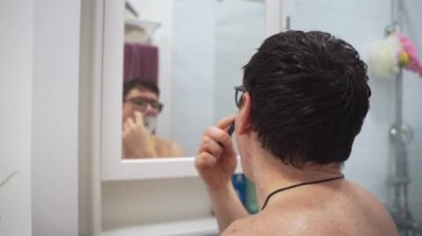 Orta yaşlı beyaz bir adam banyoda aynanın önünde sakal tıraş ediyor. Yüksek kalite 4k görüntü