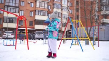 Kışın kar parkında oynayan 5-6 yaşlarında bir kız çocuğu. Yüksek kalite fotoğraf