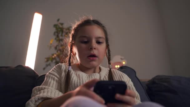 Ένα Νεαρό Κορίτσι Που Ασχολείται Ένα Smartphone Κάθεται Έναν Καναπέ — Αρχείο Βίντεο