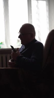 Kol askısı takan son sınıf öğrencisi pencerenin yanındaki telefona bakıyor.