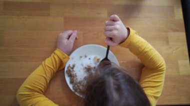 Tahta bir yemek masasında kahvaltı gevreği yiyen bir çocuğun en iyi görüntüsü. Yüksek kalite 4k görüntü