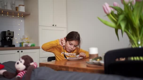 Młoda Dziewczyna Robi Śmieszne Miny Podczas Jedzenia Płatków Dobrze Oświetlonym — Wideo stockowe