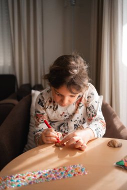 Çocuk evde deniz kabukları üzerinde yaratıcı sanatlar yapıyor, boyuyor ve çıkartmalar yapıyor. - Evet. Yüksek kalite fotoğraf