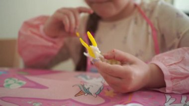 Bir çocuğun elleri tek boynuzlu at heykelciğini incelikle boyar, sanatla ilgilenir ve sanattan zevk alır. Yüksek kalite 4k görüntü