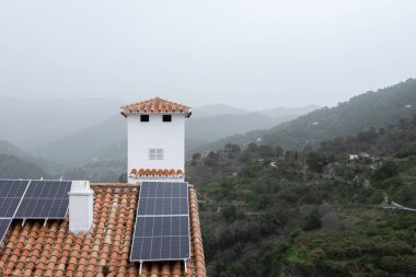 Sis kaplı bir dağ köyünde, terasotta çatılarındaki güneş panelleri yenilenebilir enerjiden faydalanıyor. Yüksek kalite fotoğraf