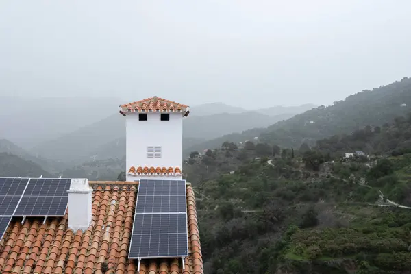 Sustainable living in a fog-covered mountain village, with solar panels on terracotta rooftops harnessing renewable energy. High quality photo