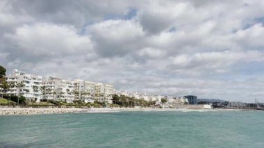 Dinamik gökyüzü altında geniş açılı deniz manzarası, bereketli palmiye ağaçları tarafından çevrelenmiş ve Akdeniz tarafından çerçevelenmiş. Yüksek kalite 4k görüntü