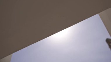 Beyaz bir duvara vuran güçlü güneş ışığı ışığı ışığı minimalist, soyut bir ışık ve gölge etkileşimi yaratır. Yüksek kalite 4k görüntü