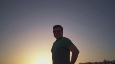 Ufukta dalgın dalgın bir adam, silueti rengarenk günbatımı gökyüzüne bakıyor. Yüksek kalite 4k görüntü