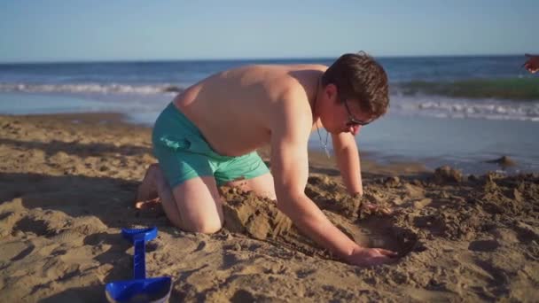 Een Vader Zwemkleding Die Zijn Kind Helpt Een Zandstructuur Bouwen — Stockvideo