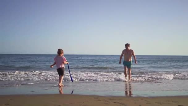 Dziecko Łopatą Dorosły Wędrują Przez Płytkie Wody Słonecznej Plaży Przechwytując — Wideo stockowe