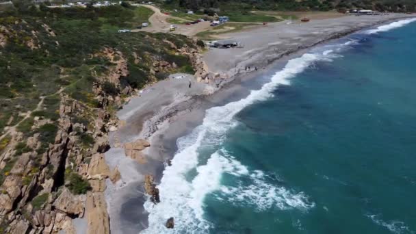 航拍捕捉到一个崎岖的海岸线 在那里蓝色的波浪与岩石海岸相遇 旁边是一个自然景观 高质量的4K镜头 — 图库视频影像