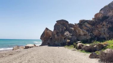 Kayalık bir çıkıntısı, mavi denizi ve berrak gökyüzü olan manzaralı bir sahilin geniş açılı görüntüsü. Yüksek kalite 4k görüntü