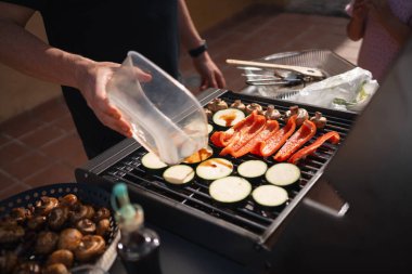 Birisi sebzeleri ızgaranın üzerine terbiye edip pişirmeye hazırlıyor. Yüksek kalite fotoğraf