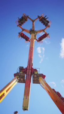  Heyecan verici bir lunapark gezisinin alçak açılı görüntüsü. Mavi gökyüzüne karşı tepetaklak giden sürücüler heyecanı ve macerayı yakalıyor. Yüksek kaliteli FullHD görüntüler