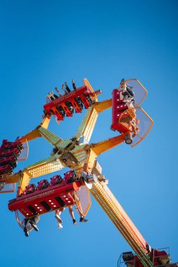 Aşağıdaki insanların, açık mavi bir arkaplanı olan bir panayırda eğlenceli bir gezintinin keyfini çıkardıkları bir manzara. Yüksek kalite fotoğraf