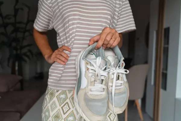 Stock image Close-up of hands holding and inspecting well-worn sneakers, emphasizing the trend of mindful consumption and sustainability. High quality photo