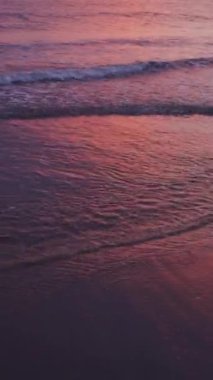 Gün batımında yumuşak okyanus dalgalarının yakın çekimleri, kıyı şeridinde pembe bir tonu yansıtıyor, doğanın güzelliğini yakalıyor. Yüksek kaliteli FullHD görüntüler