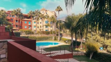  Palmiye ağaçları, terracotta binaları ve pırıl pırıl mavi bir havuzu olan pitoresk bir tatil köyü rahatlatıcı bir Akdeniz kaçışı yaratıyor. Yüksek kalite 4k görüntü