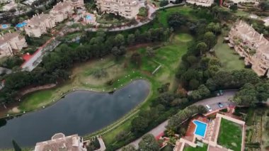 Tepelerle çevrili gölet, golf sahası ve yeşil alanların bulunduğu Akdeniz banliyö mahallesinin tepeden aşağı manzarası. Yüksek kalite 4k görüntü