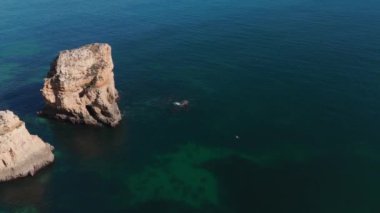 Algarve sahil şeridine geniş bir hava manzarası, engebeli uçurumlar ve sakin, yeşil sular. Huzurlu ve resimli bir seyahat yeri. Yüksek kalite 4k görüntü