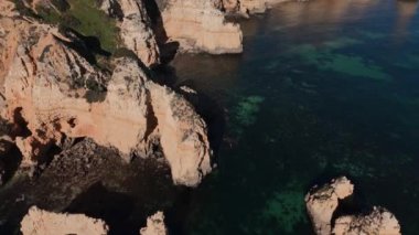 Algarve sahil şeridine geniş bir hava manzarası, engebeli uçurumlar ve sakin, yeşil sular. Huzurlu ve resimli bir seyahat yeri. Yüksek kalite 4k görüntü