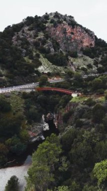 Endülüs kırsalının canlı yeşil ve kırmızı renkleriyle çevrili kayalık bir kanyon ve tahta bir köprü manzarası. Yüksek kalite 4k görüntü